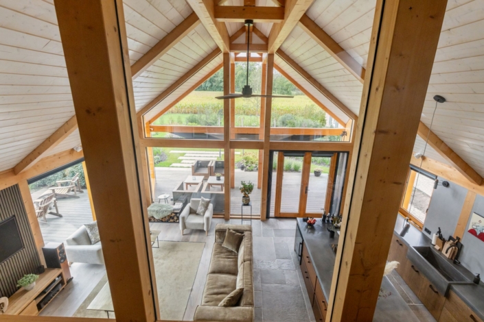Ruime woonkamer in modern houten huis met grote driehoekige ramen, groen uitzicht, gezellige zithoek, eettafel en open keuken, natuurlijk valt er licht binnen. Finnhouse houten huizen comfort en design. - Finnhouse
