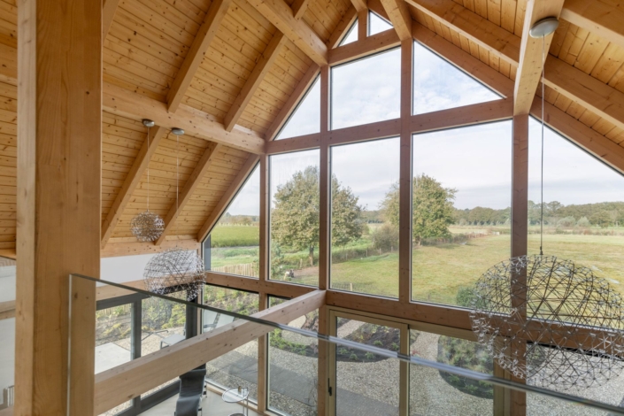 Moderne Finnhouse met hoog houten plafond, grote glazen ramen die uitkijken op een groen landschap, twee metalen lampen en een gezellige sfeer voor bijeenkomsten met gezin op het balkon. - Finnhouse
